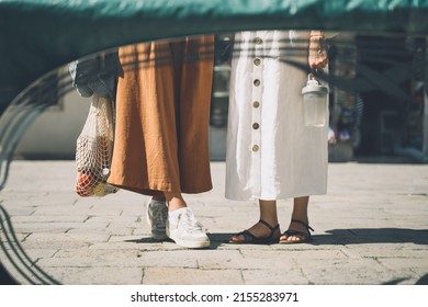 Young women shopping in flea market in Venice. Two girls in clothes made of natural fabrics reflected in antiques mirror. Travel and Vacation in Europe.