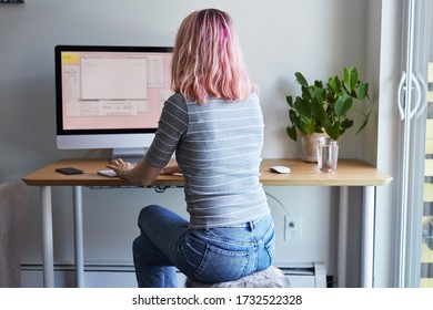 Young Women Sitting By Her Desk In A Home Office Environment, Working On A Desktop Computer