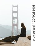 Young women sitting in the Presidio National Park in San Francisco California overlooking the Golden Gate Bridge