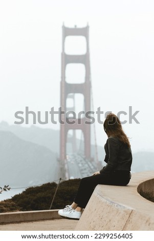 Young women sitting in the Presidio National Park in San Francisco California overlooking the Golden Gate Bridge