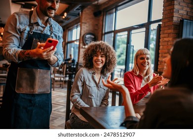 Young women smiling, talking and ordering to waiter at the cafe restaurant - Powered by Shutterstock