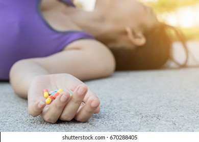 young women in sportswear falling lose consciousness on sidewalk trying to eat diet pills in hand