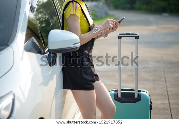 Young women with suitcases and use smartphone.\
Vacation concept. Car trip. Summer vacation. women traveling with\
suitcases, walking on the\
road