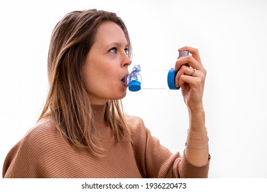 Young Women Taking Asthma Medication With An Inhaler And Spacer For Proper Use.