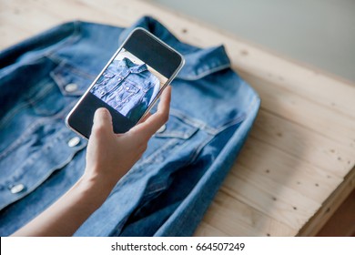 young Women taking photo to shirts with cell telephone or smartphone digital camera for Post to sell Online on the Internet .