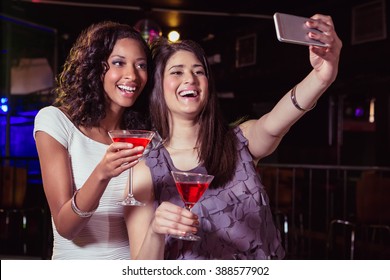 Young Women Taking A Selfie While Having A Cocktail Drink In Bar