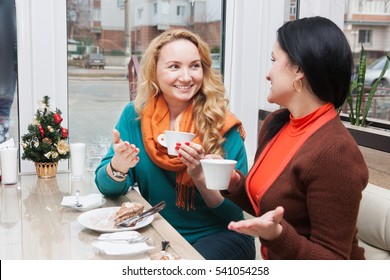 Young women talking and drinking coffee in a small cafe - Shutterstock ID 541054258