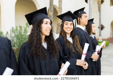 Young women at their graduation ceremony smiling making eye contact and looking happy while receiving their college diplomas  - Shutterstock ID 2278104691