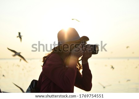 Young women wear hat taking a photo while the sunset