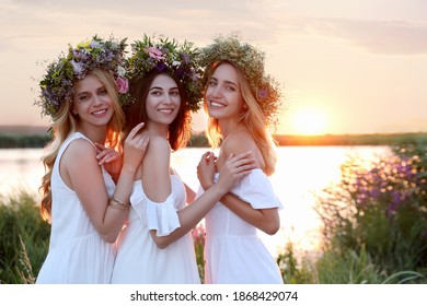 Young women wearing wreaths made of beautiful flowers outdoors at sunset - Powered by Shutterstock