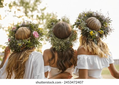 Young women wearing wreaths made of beautiful flowers outdoors on sunny day, back view - Powered by Shutterstock