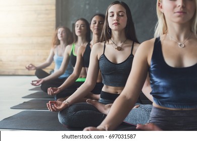 Young Women In Yoga Class Making Meditation Lotus Pose, Copy Space, Crop. Healthy Lifestyle In Fitness Club.