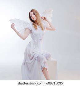 Young and wonderful blonde girl in the image of an angel with white wings.