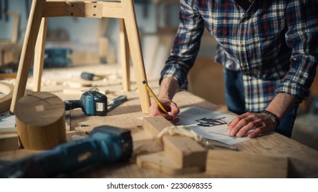 Young Woodworker Checking the Layout Manual of a Stylish Handmade Wooden Chair. Talented Furniture Designer Working in a Workshop in a Creative Loft Space with Tools and Equipment. - Shutterstock ID 2230698355