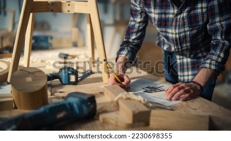 Young Woodworker Checking the Layout Manual of a Stylish Handmade Wooden Chair. Talented Furniture Designer Working in a Workshop in a Creative Loft Space with Tools and Equipment.