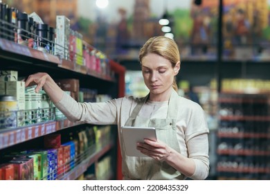 A young worker in an apron is taking inventory in a supermarket, store. He stands with a notebook - Powered by Shutterstock