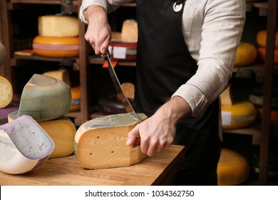 Young Worker Cutting Cheese In Shop