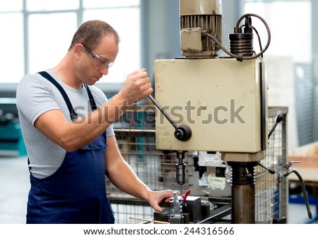 young worker in factory using drill machine