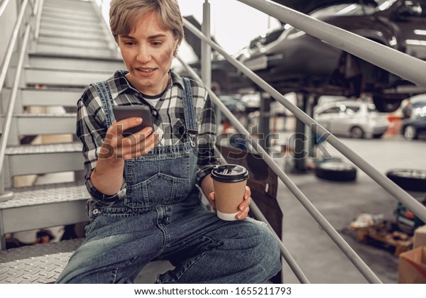 Young\
worker with a gadget relaxing on the\
staircase