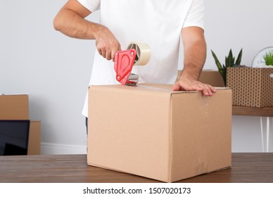 Young worker packing cardboard box in room, closeup. Moving service - Powered by Shutterstock