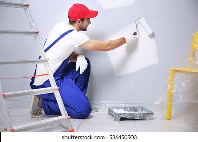 Young Worker Painting Wall In Room