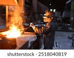 young worker in protective clothing at work at the blast furnace in an iron foundry - closeup photo