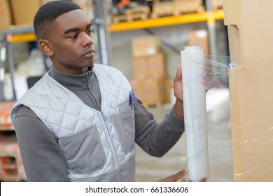 Young Worker Shrink Wrapping Pallet