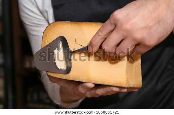 Young worker slicing cheese\
in shop