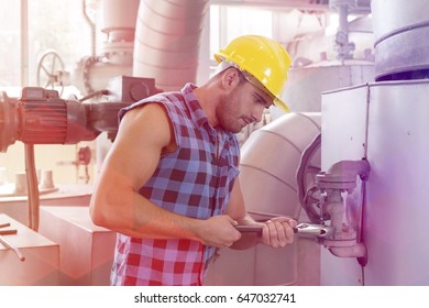 Young worker using wrench on industrial machine