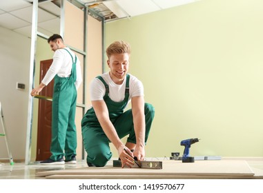 Young Workers Installing Drywall Indoors. Home Repair Service