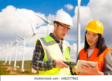 Young workers looking and checking wind turbines at field