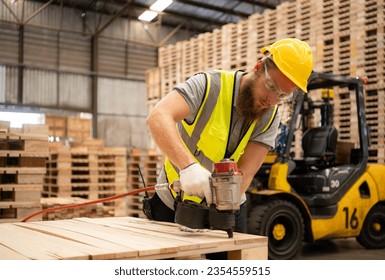 Young workers working in a woodworking factory, Using a nailing machine to assemble wooden pallets - Powered by Shutterstock