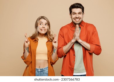 Young worried couple two friends family man woman wear casual clothes keeping fingers crossed hold hands folded in prayer gesture, beg together isolated on pastel plain light beige color background - Powered by Shutterstock