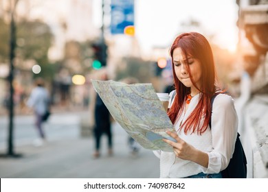 Young Worried Female Traveler Lost In The City Using Map
