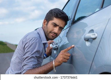 Young worried funny looking man obsessing about cleanliness of his new car. Car care and protection concept