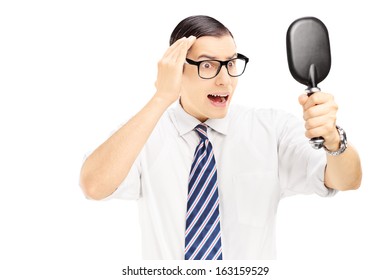 Young Worried Man Checking For Thinning Hair In The Mirror Isolated On White Background