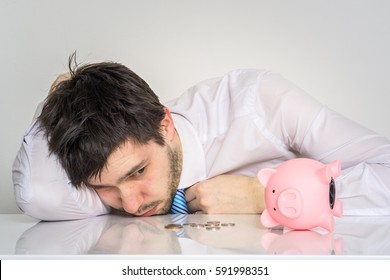 Young worried man has empty piggy money bank.