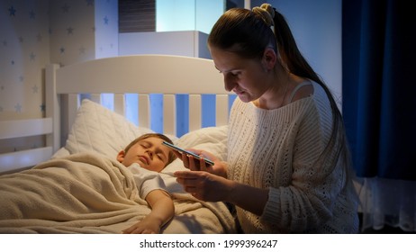 Young Worried Mother Calling Doctor By Phone At Night. Concept Of Children Illness, Disease And Parent Care