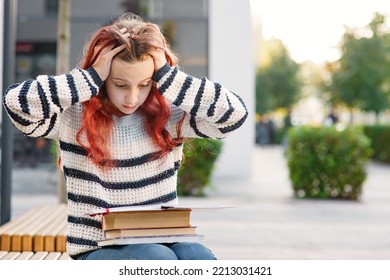 Young Worried Tired Girl Looking At Books On Her Knees With Desperation And Running Her Hands Through Her Hair, Sitting On Bench At The City Street- Emotional Portrait, Stress Of Studying, Schooling