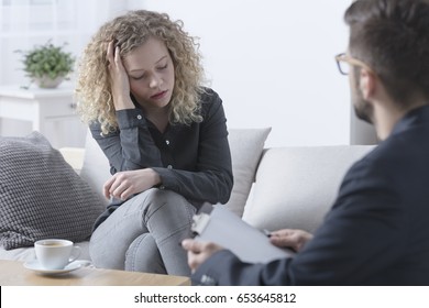 Young worried woman touching her head during psychotherapy