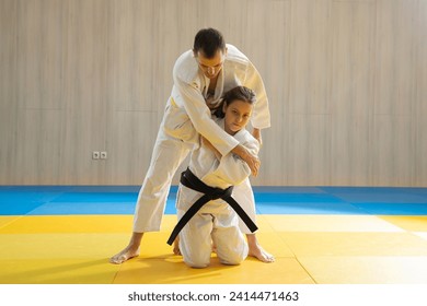 Joven judo de cinturón amarillo en judogi blanco y joven judo de cinturón negro en judogi blanco
