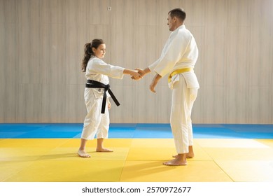 Young yellow belt judo man in white judogi and young black belt judo girl in white judogi