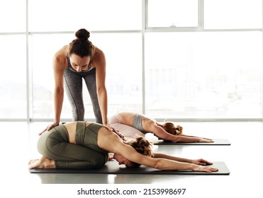 Young Yoga Instructor Standing At Woman And Adjusting Her Childs Pose At Group Class