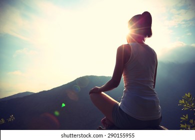 young yoga woman sit meditation on sunrise mountain peak rock - Powered by Shutterstock