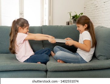 Younger And Older Girls Fighting For Laptop Arguing Over Playing On The Internet. Lifestyle Portrait Of Sisters Not Sharing Computer In Relationship Between Siblings And Technology Addiction Concept.