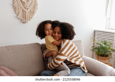 Younger and older sister spending time together at home. Two black girls of different age hugging and showing affection. Black female siblings having fun and bonding. Background, copy space, close up.