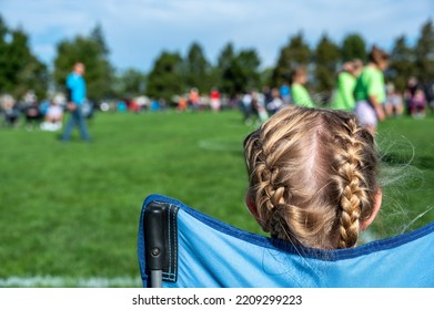 Younger Sister Watching A Soccer Game To Support Her Sibling. 