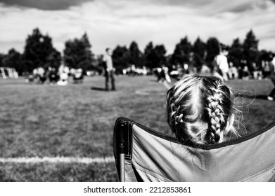 Younger Sister Watching A Soccer Game To Support Her Sibling. 