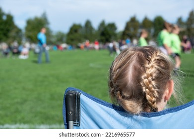 Younger Sister Watching A Soccer Game To Support Her Sibling. 