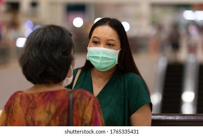 Younger Woman Talking With Elderly Woman While Wearing Face Mask.